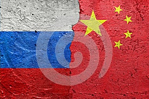 Russia vs China - Cracked concrete wall painted with a Russian flag on the left and a Chinese flag on the right stock photo