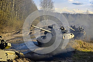 Russian armored combat vehicles are navigating through marshland through forests.