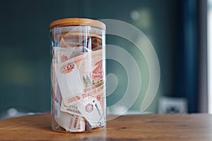 Russian banknotes of 5000 rubles packed in a glass jar on a kitchen. Business, finance concept. Saving money.