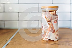 Russian banknotes of 5000 rubles packed in a glass jar on a kitchen. Business, finance concept. Saving money.