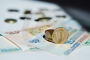 Russian banknotes rubles and a coin with a face value of 10 lie on a white surface. The concept of Economics