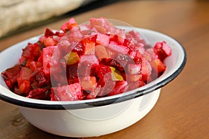 Russian beet salad vinaigrette in rustic bowl on wooden table