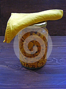 Russian and Belarussian cuisine : Pickled young Chanterelle mushrooms in a jar, marinaded chanterell in glass on brown wooden back