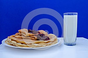 Russian blini pancakes witg glass of milk on blue background . Foodphotography