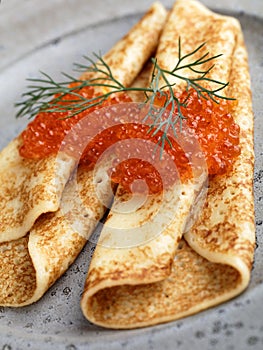 Russian Blinis with red caviar on a gray plate closeup