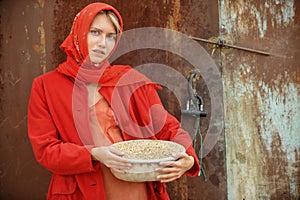 Russian blonde with blue eyes in a red kerchief is working on the farm. The concept of female beauty and perfection