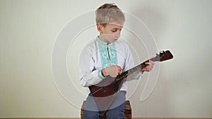 Russian boy in national dress plays the balalaika.