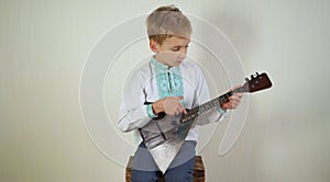 Russian boy in national dress plays the balalaika.