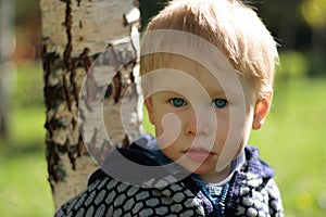 Russian boy stands near the birch
