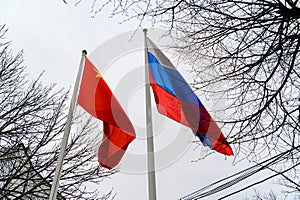 Russian and Chinese flags are flying in the wind. Flags of Russia and China on flagpoles