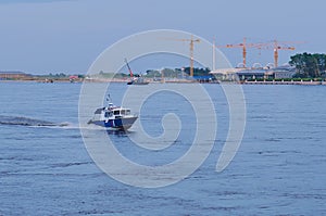 A Russian Coast Guard boat patrols a section of the Amur River. In the background, the Chinese customs building and