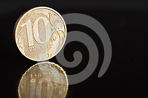 Russian coin ten roubles on the edge on black background with reflection with copy space