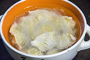 Russian dumplings in broth in an orange plate