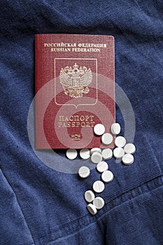 Russian Federation passport and scattered medical pills on blue