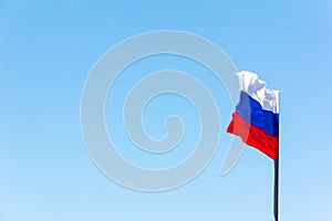 The Russian flag fluttering in the wind against the blue sky.