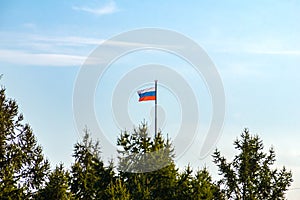 the Russian flag is visible above the coniferous forest on a flagpole with a warning red signal lamp