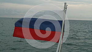 Russian flag waving in the background of the glare on the water