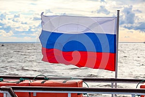 Russian flag waving on the deck of the ship against the background of the sea