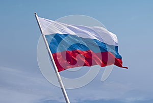 Russian flag waving in the wind over blue sky