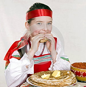 Russian girl eats pancakes with red caviar.