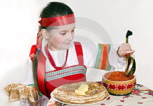 Russian girl eats pancakes with red caviar.