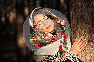 Russian girl in headscarves near the tree in the forest