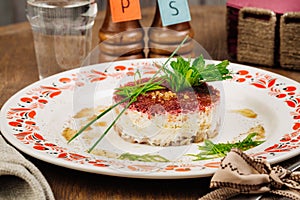 Russian herring salad on plate on wooden table