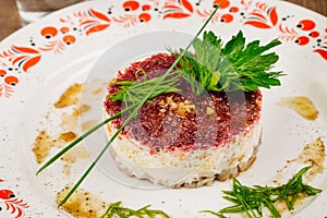 Russian herring salad on plate on wooden table