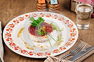 Russian herring salad on plate on wooden table