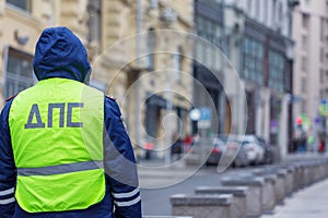 Russian inspector of traffic police patrol standing on the street in the center of Moscow in yellow vest jacket with a sign DPS photo