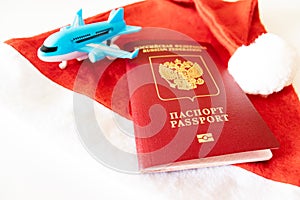 Russian international passport, blue toy plane and red santa hat on white background