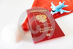Russian international passport, blue toy plane and red santa hat on white background