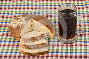 Russian kvas in mug and slices of bread on tablecloth