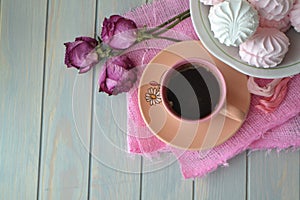 Russian marshmallowor zefir with pink cup of coffee on light teal wooden table. Top view, vintage style, dry roses. Empty place