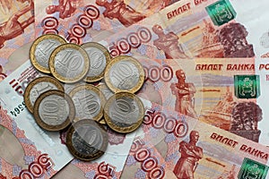 Russian money of five thousands denominations and commemorative coins lie on the table mixed