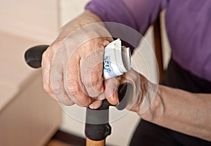 Russian money in the hand of an elderly woman with a cane.
