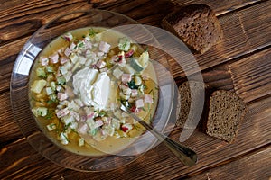 Russian national cuisine. Okroshka with sour cream. Cold soup with meat, vegetables and kvass. Two slices and a loaf of brown