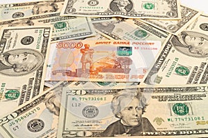 Russian national currency on top of US dollar banknote, top view of mixed rouble banknotes. Russian and American paper money.
