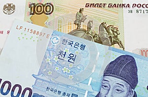 A Russian one hundred ruble note paired with a blue and white one thousand won bill from Korea.