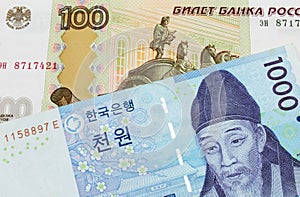 A Russian one hundred ruble note paired with a blue and white one thousand won bill from Korea.