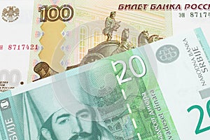 A Russian one hundred ruble note paired with a green and white twenty dinar banknote from Serbia.