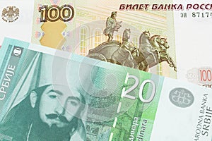 A Russian one hundred ruble note paired with a green and white twenty dinar banknote from Serbia.