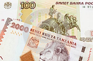 A Russian one hundred ruble note paired with a orange and white 2000 shilling bill from Tanzania.