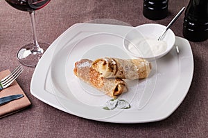 Russian pancake folded on a white plate on the dark background