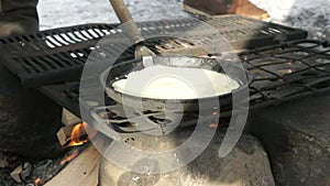 Russian pancakes on frying pan on bonfire