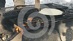 Russian pancakes on frying pan on bonfire