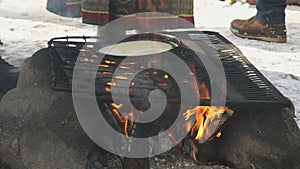 Russian pancakes on frying pan on bonfire