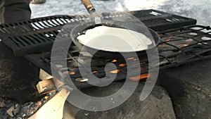 Russian pancakes on frying pan on bonfire