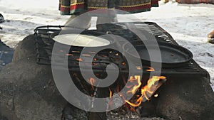 Russian pancakes on frying pan on bonfire