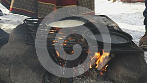 Russian pancakes on frying pan on bonfire